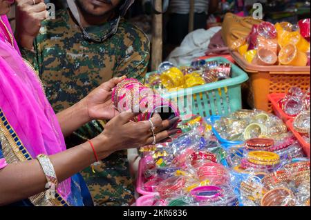 Rajasthani-Frau probiert bunte Armreifen aus. Armreifen werden auf dem berühmten Sardar-Markt und im Ghanta Ghar Uhrenturm in Jodhpur, Rajasthan, Indien verkauft. Stockfoto