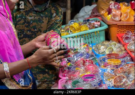 Rajasthani-Frau probiert bunte Armreifen aus. Armreifen werden auf dem berühmten Sardar-Markt und im Ghanta Ghar Uhrenturm in Jodhpur, Rajasthan, Indien verkauft. Stockfoto