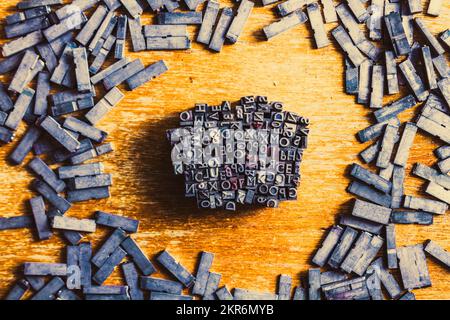 Retro-Industriedrucker legen das Buchdruckkonzept auf eine Streuung von Satzblöcken mit verschlungenem Buchstaben und Zahlen. Vintage Writers Block Stockfoto