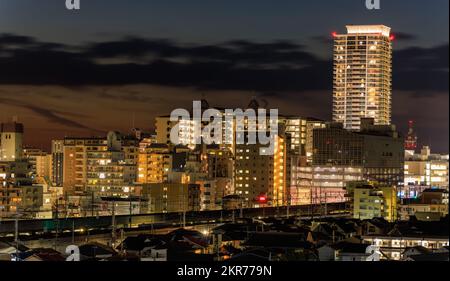 Hochhaus über Wohngebäuden in einer kleinen Stadt nach Sonnenuntergang Stockfoto