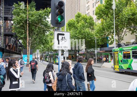 Hook Turn Road Rule Schild im Stadtzentrum von Melbourne, Fahrzeuge und Fahrräder biegen von der linken Spur rechts ab, Melbourne Tram fährt vorbei, Victoria, Australien Stockfoto