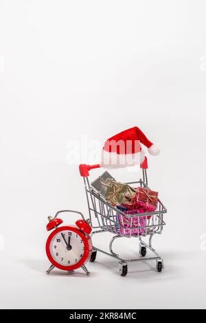 Ein Einkaufswagen voller Last-Minute-Weihnachtsgeschenke und einem roten Wecker. Stockfoto