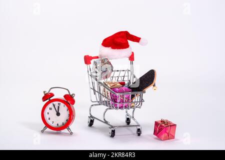 Ein Einkaufswagen voller Last-Minute-Geschenke und ein roter Wecker, der den Zeitdruck an Weihnachten anzeigt. Stockfoto