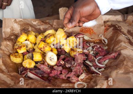 Mitchopo (gegrilltes Fleisch), serviert in der Zeitung, in der es gekocht wird, Kamalondo, Luubumbashi, Demokratische Republik Kongo. Stockfoto
