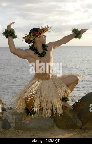 Der männliche Hula-Tänzer posiert am Strand in einer traditionellen Sonnenanbetungsbewegung. Stockfoto