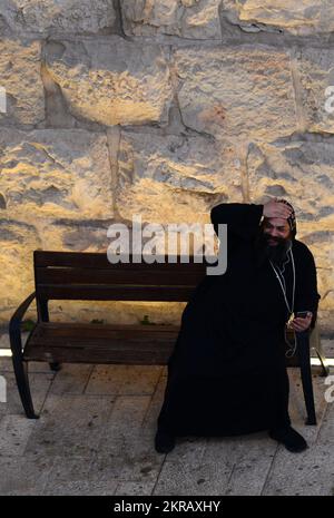 Ein koptischer Priester, der sein Smartphone am neuen Tor, der Altstadt von Jerusalem, Israel, benutzt. Stockfoto