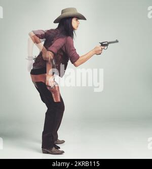 Im Sheriff um diese Teile...Ganzlängenaufnahme einer attraktiven jungen Frau in Cowboy-Kleidung. Stockfoto