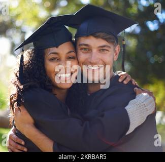 Beste Freunde und Absolventen. Porträt von zwei Schülern, die sich am Abschlusstag umarmen. Stockfoto