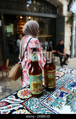 Genießen Sie ein kaltes palästinensisches Taybritbier in einem Café/einer Bar in der lebhaften New Gate Street im christlichen Viertel in der Altstadt von Jerusalem. Stockfoto