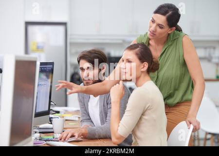 Teamwork sorgt für einen reibungslosen Ablauf des Projekts. Eine junge Geschäftsfrau, die ihren Kollegen etwas am Computer zeigt. Stockfoto