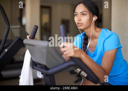 Ganzkörpertraining. Eine junge ethnische Frau, die im Fitnessstudio auf einem Heimtrainer trainiert. Stockfoto