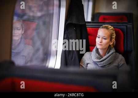 Genießen Sie die friedliche Fahrt. Eine attraktive junge Frau, die mit dem Zug reist. Stockfoto