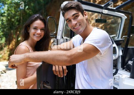 Allradantrieb - die einzige Möglichkeit. Porträt eines jungen Paares, das sich gegen die offene Tür eines 4x4 lehnt. Stockfoto
