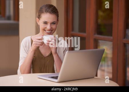 Genießen Sie einen entspannten Morgen. Eine attraktive junge Frau, die Tee trinkt, während sie ein Notebook benutzt. Stockfoto