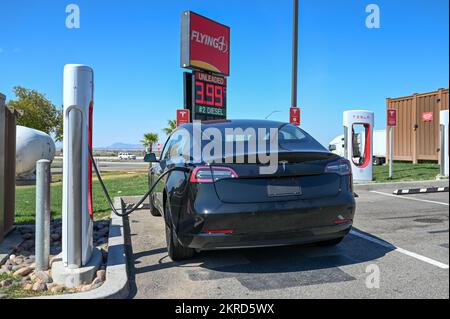 Ein Tesla Model 3 wird mit einer Supercharger-Station vor einem Flying J Travel Center am Dienstag, den 27. September 2022, in Ehrenburg, Arizona, gesehen (Dylan Stewart/Imag Stockfoto