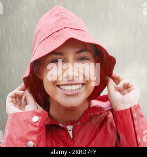 Ein bisschen Regen bringt mich nicht runter. Eine attraktive junge Frau, die im Regen steht. Stockfoto