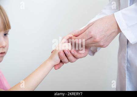 Ein Neurologe untersucht den pathologischen Reflex eines hoffmans bei einem Mädchen auf Neuropathologien. Nervensystem Stockfoto