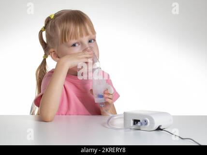 Schönes kleines Mädchen, das zu Hause bei Asthma und Lungenentzündung in einen Inhalator atmet. Behandlung von Erkrankungen der oberen Atemwege bei Kindern. Co Stockfoto