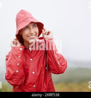 Es sieht nach Regen aus... aber ich bin bereit dafür. Eine attraktive junge Frau, die im Regen steht. Stockfoto