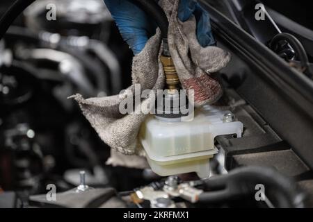 Renningen, Deutschland. 28.. November 2022. Ein Werkstattmitarbeiter wechselt die Bremsflüssigkeit während der Wartung eines Mazda MX-30. Kredit: Marijan Murat/dpa/Alamy Live News Stockfoto