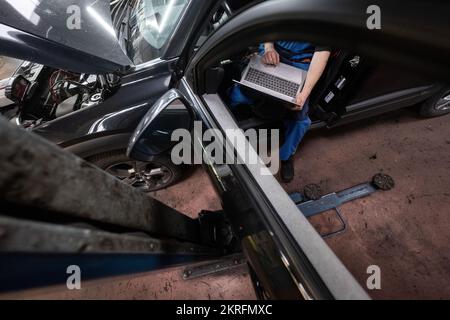 Renningen, Deutschland. 28.. November 2022. Ein Werkstattmitarbeiter führt während der Wartung eines Mazda MX-30 ein Software-Update durch. Kredit: Marijan Murat/dpa/Alamy Live News Stockfoto