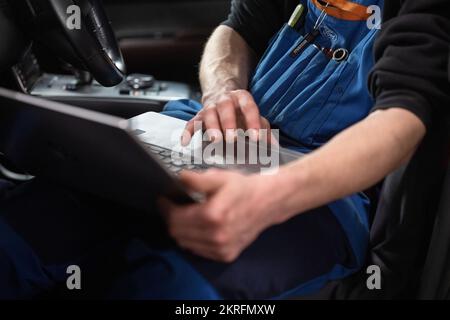 Renningen, Deutschland. 28.. November 2022. Ein Werkstattmitarbeiter führt während der Wartung eines Mazda MX-30 ein Software-Update durch. Kredit: Marijan Murat/dpa/Alamy Live News Stockfoto