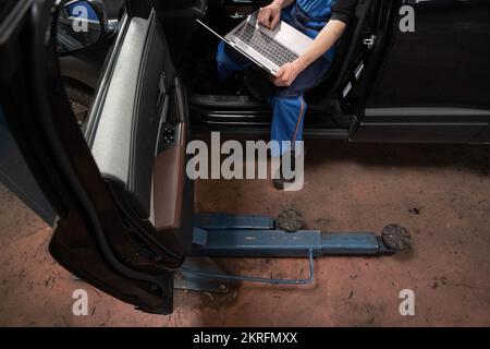 Renningen, Deutschland. 28.. November 2022. Ein Werkstattmitarbeiter führt während der Wartung eines Mazda MX-30 ein Software-Update durch. Kredit: Marijan Murat/dpa/Alamy Live News Stockfoto