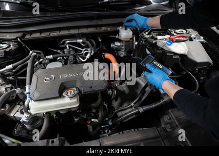 Renningen, Deutschland. 28.. November 2022. Ein Werkstattmitarbeiter prüft den Wassergehalt der Bremsflüssigkeit während der Wartung eines Elektroautos des Mazda MX-30. Kredit: Marijan Murat/dpa/Alamy Live News Stockfoto