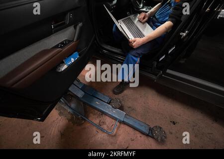 Renningen, Deutschland. 28.. November 2022. Ein Werkstattmitarbeiter führt während der Wartung eines Mazda MX-30 ein Software-Update durch. Kredit: Marijan Murat/dpa/Alamy Live News Stockfoto