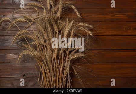 Weizenkörner oder Roggenspitzen auf Holztisch, für Getreidebrotmehl. Reichhaltiges Erntekonzept. Stockfoto