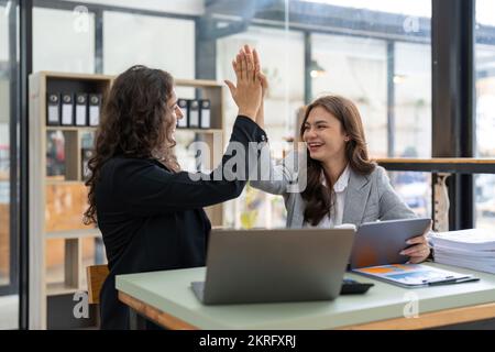 Zwei glückliche, freundliche und vielseitige Profis, fröhliche, erfolgreiche Kollegen von Geschäftspartnern, die mit High Five einen geschäftlichen Triumph im Amt feiern Stockfoto