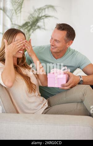 Okay, ich werde nicht hinsehen. Ein gutaussehender Mann, der seine Frau mit einem Geschenk überraschte. Stockfoto