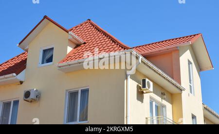 Nahaufnahme auf dem Dach des Hauses mit Kunststoff-Regenrinnen-Pipeline, Soffit und Armaturenbrettern. Dachrinnen in Problembereichen. Stockfoto