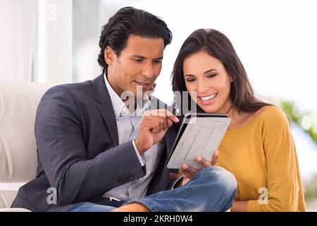 Ich wollte das mit dir teilen. Ein Ehemann, der seiner Frau etwas auf seinem digitalen Tablet zeigt. Stockfoto