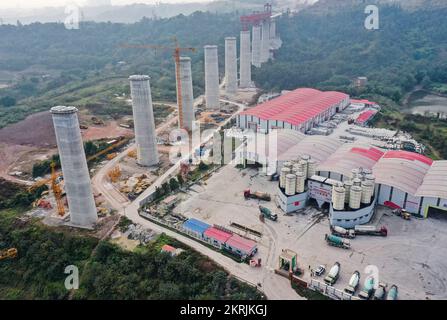 Chongqing. 28.. November 2022. Dieses Luftfoto wurde am 28. November 2022 aufgenommen und zeigt eine Betonfabrik und die Huafu-Mega-Brücke, die im Bau am Abschnitt Sichuan-Chongqing der Hochgeschwindigkeitsbahn Chongqing-Kunming in der Gemeinde Chongqing im Südwesten Chinas steht. Die 699 km lange Hochgeschwindigkeitsbahn Chongqing-Kunming mit einer geplanten Geschwindigkeit von 350 km/h ist ein wichtiger Bestandteil des Eisenbahnkorridors, der die chinesische Hauptstadt Peking mit Kunming in der südwestchinesischen Provinz Yunnan verbindet. Kredit: Wang Quanchao/Xinhua/Alamy Live News Stockfoto