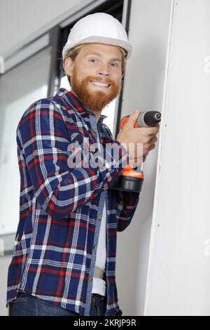 Junger Handwerker mit Elektrobohrer Stockfoto