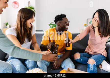 Eine Gruppe junger, multiethnischer, glücklicher Freunde, die zu Hause abhängen Stockfoto