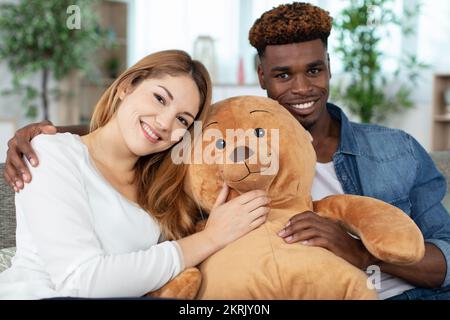 Ein Paar saß auf der Couch mit einem großen Teddybären Stockfoto