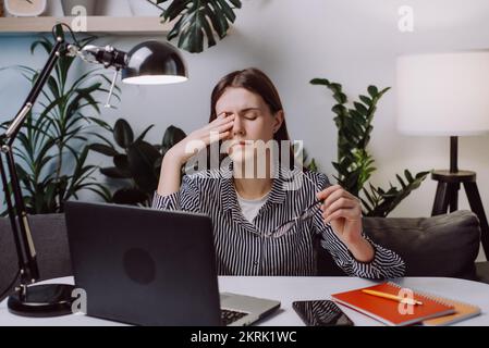 Gestresstes Mädchen leidet an Kopfschmerzen Sehstörungen Sitzen am Heimtisch mit Laptop. Stockfoto