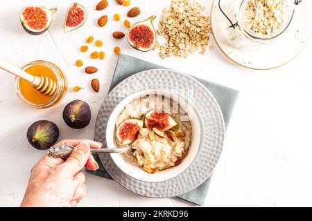 Eine Frau hält einen Löffel mit Haferflocken gefüllt während des Frühstücks. Haferflocken mit Obst in einer Schüssel. Gesunde Ernährung. Entgiftung Stockfoto