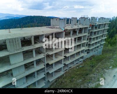 Das mehrstöckige verlassene Hotel mit Betonwänden befindet sich in einem dichten Fichtenwald am Hang des hohen Tals der Rhodope Mountains Stockfoto