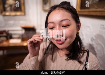 Junge weibliche asiatische Inhalationsaroma ätherischen Öls auf Testpapier bei der Zubereitung von Parfüm zu Hause Stockfoto