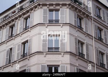 Außenansicht eines alten Wohngebäudes in grauer Farbe mit Glasfenstern und Balkonen in Paris Stockfoto