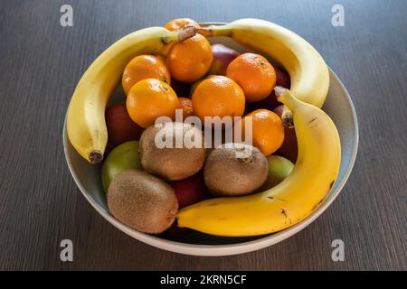 Eine Schüssel mit gemischten Zitrusfrüchten, Äpfeln, Satsumas, Kiwis und Bananen - eine gute Faserquelle und 5 pro Tag. Konzept - gesunde Ernährung, essen mehr Obst Stockfoto