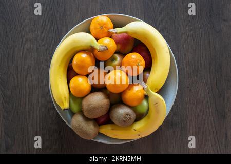 Eine Schüssel mit gemischten Zitrusfrüchten, Äpfeln, Satsumas, Kiwis und Bananen - eine gute Faserquelle und 5 pro Tag. Konzept - gesunde Ernährung, essen mehr Obst Stockfoto