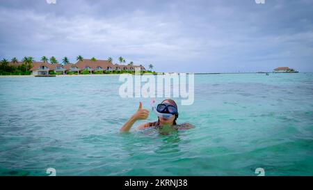 Eine Frau in einem roten Bikini schnorchelt fröhlich auf den Malediven. Stockfoto