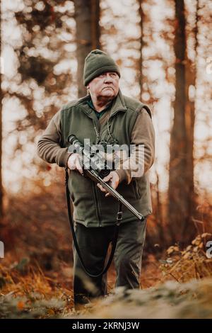 Herbstjagd, Jäger mit Gewehr, der nach wilden Tieren im Wald oder Wald Ausschau hält, Outdoor-Sportkonzept Stockfoto