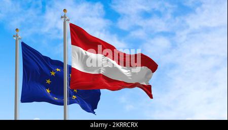 Die Flaggen Österreichs und der Europäischen Union winken an einem sonnigen Tag im Wind. Demokratie und Politik. Europäisches Land. Nahtlose Schleife in Zeitlupe. Stockfoto