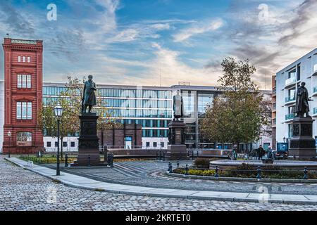 SchinkelplatzMitte, Berlin. Platz mit rekonstruierter Ecke der Bauakedemie-Fassade und Gedenkstatuen Stockfoto