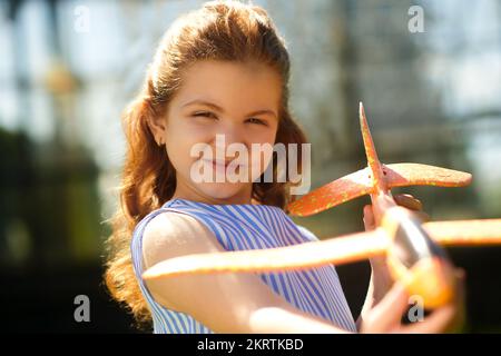 Porträtfoto eines Ingwermädchens mit einem Spielzeugflugzeug Stockfoto